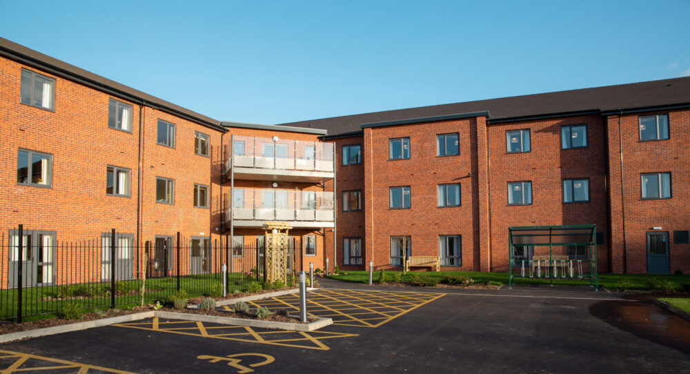Cloverleaf from the rear courtyard — three-storey brick with central balcony